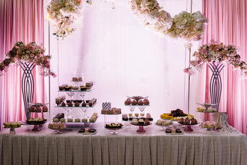 Delicious wedding reception. Candy bar decorated with flowers for banquet. Celebration concept.Table with sweets, candies, dessert.