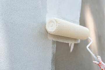 Painting of walls in a white color. Close-up house paint roller, home improvements, horizontal view...