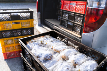 Delivery truck is parked outside near bakery or storehouse on sunny winter day. Loading and unloading food products. Fresh Christmas pies Christstollen in containers in trunk. Holiday gifts, present