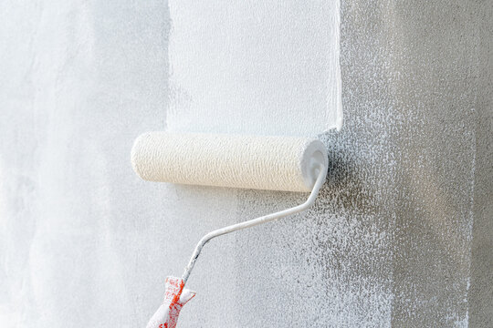 Painting of walls in a white color. Close-up house paint roller, home improvements, horizontal view with copy space.	
