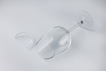 Broken wine glass with a shard on a light isolated background