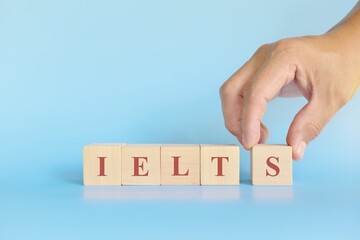 IELTS or international english language testing system exam or test concept. Wooden blocks typography flat lay on blue background.