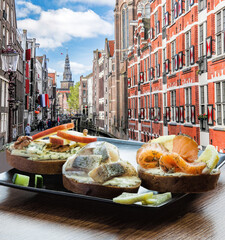 Amsterdam city with fish plate (salomon and codfish sandwiches) against canal in Netherlands
