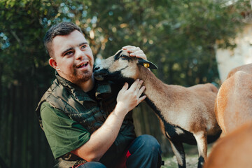 Caretaker with down syndrome taking care of animals in zoo, stroking goat. Concept of integration...