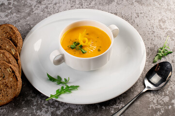 Fresh and healthy pumpkin cream soup with herbs. Vegan cuisine