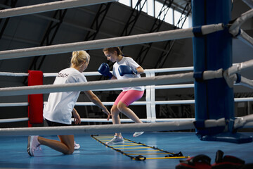 Workout with coach. School age girl, beginner kickboxer training with personal trainer at sports...