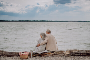 Senior couple relaxing and looking at autumn sea.