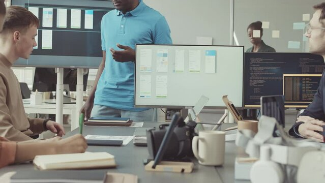 Diverse software developers discussing programming and coding while having meeting at office desk at modern IT company