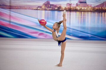 girl gymnast performs an element with a ball