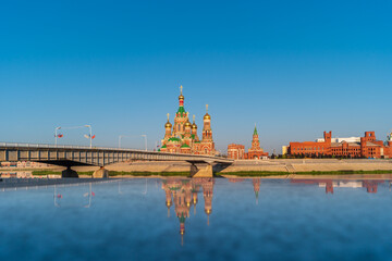 Obraz premium Yoshkar-Ola, Russia. View of Cathedral of the Annunciation of the Blessed Virgin Mary and Blagoveshhenskaya Tower on the embankment of the Kokshaga river wiht reflection.