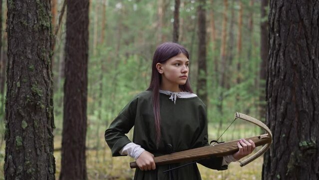 girl with crossbow in hands walks through