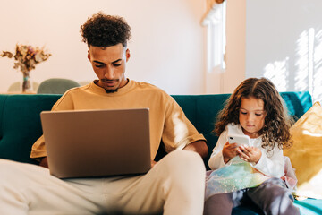 Father and daughter using their technology devices at home