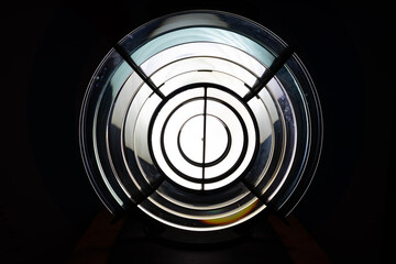 Big spotlight in the dark. Frontal view of the lens of a lamp in a lighthouse. Geometric. Reminiscent of a crosshair when hunting. Abstract background