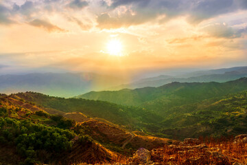 beautiful highland landscape with amazing view from a top with golden grass and green bushes to a canyon with majectic mountains and scenic cloudy sunset on background