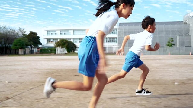学校の校庭を走っている小学生の男の子と女の子