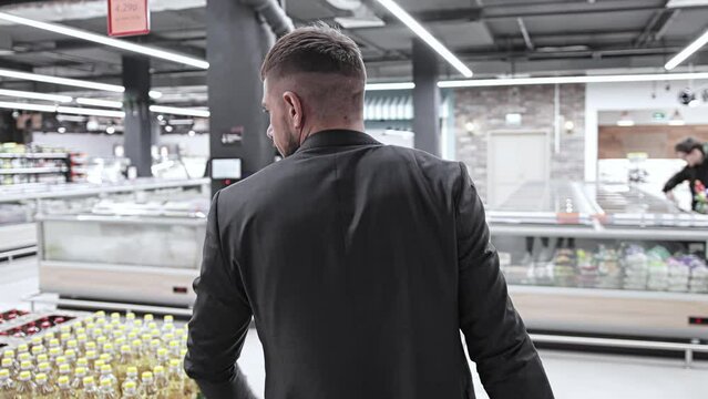 Positive cheerful customer 30 35 years old speaks to camera in grocery store. Male caucasian buyer with mustache in shopping mall centre supermarket. Happy shopaholic. Sales promotions discounts