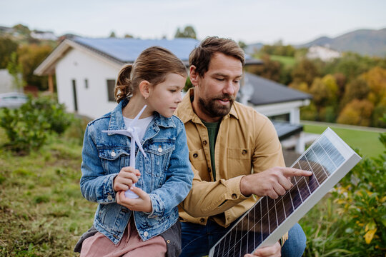 Father showing his little daughter solar photovoltaics panels, explaining how it works. Alternative energy, saving resources and sustainable lifestyle concept.