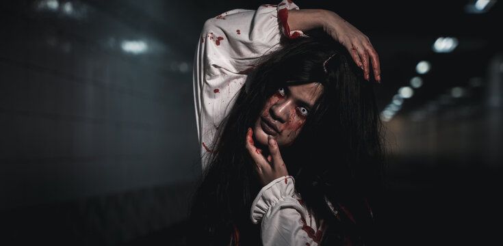Horror bloodthirsty woman ghost or zombie she is horror scary with breaks her neck at dark night, Screaming zombie female face with blood, Happy halloween day festival concept