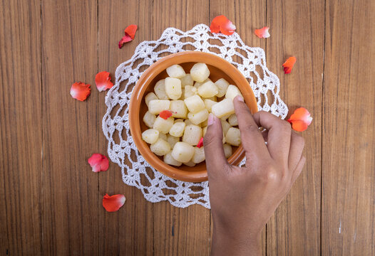 A girl picking up Chena Murk in a bowl, chena murki is a bite-size dry sweet made with paneer dipped in sugar syrup 