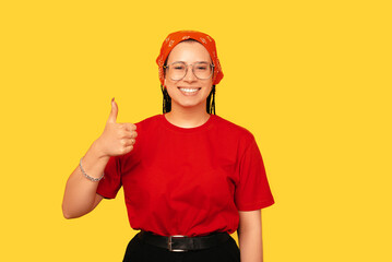 Smiling young woman with box braids is showing thumb up to the camera.