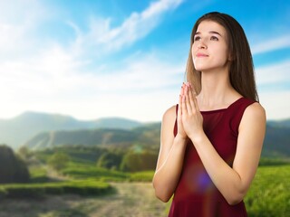 Young person praying on beautiful nature background.