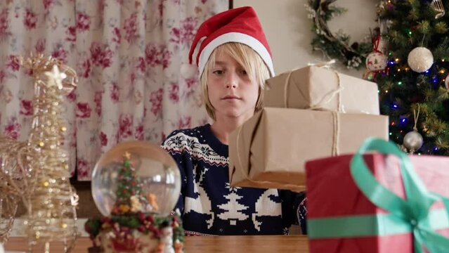 Kid with Santa hat preparing Christmas gifts indoors