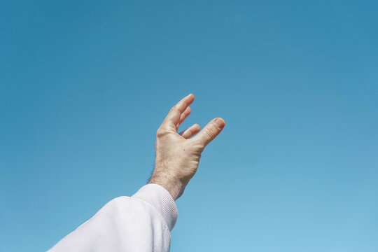 hand up in the air gesturing in the blue sky, blue background
