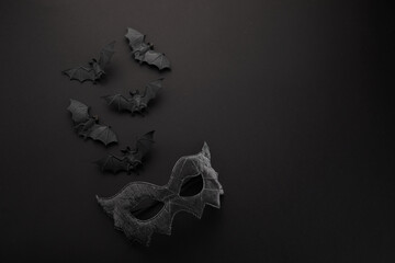 Halloween concept - black bats and mask on black background.