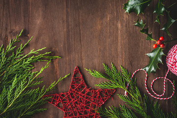 fondo de Navidad: ramas de acebo y ciprés, adorno de estrella roja, rama de acebo y cordón rojo y...