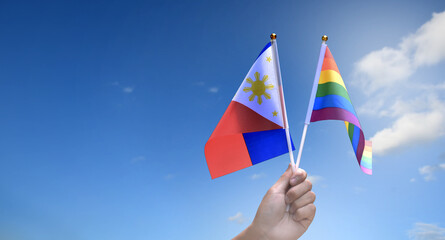 Rainbow flag and Philipines national flag holding in hand, soft and selective focus, concept for celebration of lgbtq+ in pride month around the world.