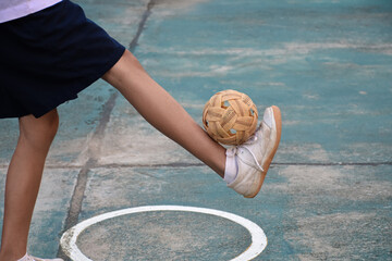 Young southeast asian female sepak takraw player using her right ankle to hold ball up on the...