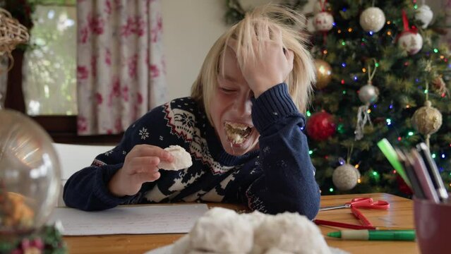 Funny kid eating greek christmas cookies with almond Kourabiedes and laughing.