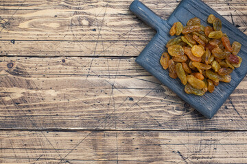Dried raisins from white grapes on a wooden chopping board.
