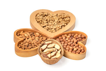 Variety of nuts in wooden cups in the shape of a heart isolated on a white background.