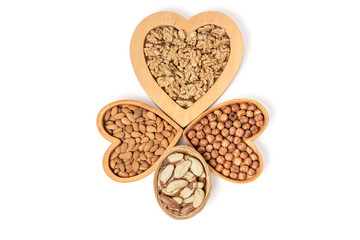 Variety of nuts in wooden cups in the shape of a heart isolated on a white background.