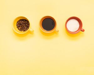 Mug filled with coffee beans, espresso, latte macchiato on bright yellow background with copy...