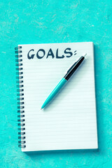 Goal Setting. Handwritten word Goals with a ballpoint pen and a notepad, overhead flat lay shot on...