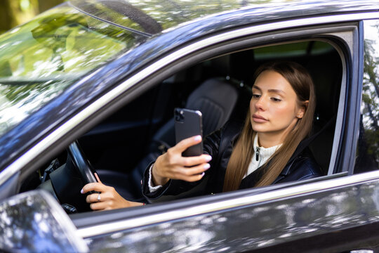 Young woman taking picture with phone camera in car
