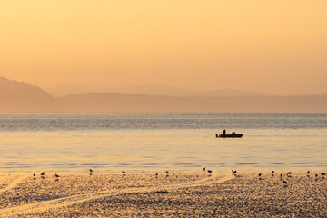 Morning seascape at sunrise. View of the shallows, the sea bay and the fishing boat in the sea....