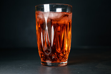 an orange drink with ice in a glass. a drink in a glass isolated on a black background. a drink background in a bar