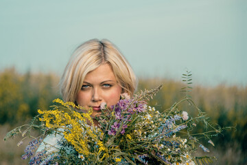 Beautiful blonde with a bouquet of wildflowers. A young woman holds a bouquet of wildflowers