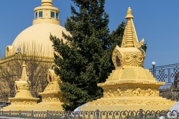 Fototapeta premium Small yellow stupas decorated with ornaments against the backdrop of a large Buddhist stupa 