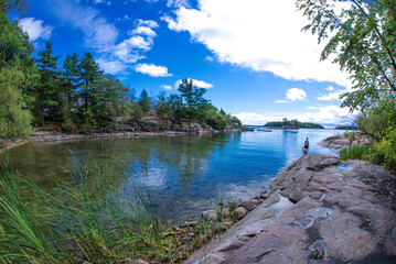 Beau Rivage Island bay surrounded by rocks and forest with a woman and her dog