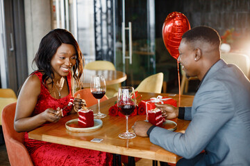Romantic black couple sitting at restaurant wearing elegant clothes