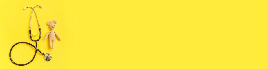 Simply minimal design toy bear and medicine equipment stethoscope isolated on yellow background. Health care children doctor concept. Pediatrician symbol. Flat lay top view layout copy space banner © Юлия Завалишина