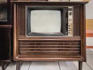 Retro TV with wooden case in room with vintage wallpaper. Old and classic technology
