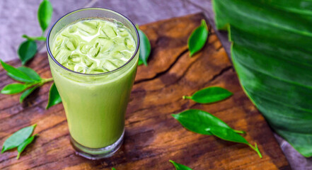 iced matcha latte, green tea with milk in a  glass with ice on wooden
