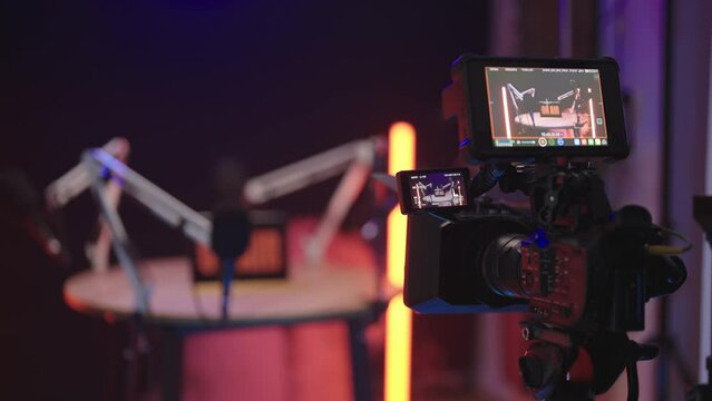 Podcast talk show in black studio with red neon lights from behind the camera 4K