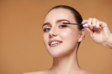 woman applying black mascara on long eyelashes with a brush