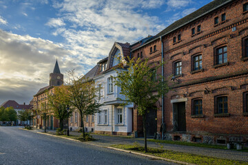 Fototapeta na wymiar Denkmalgeschützte Häuserzeile in Beeskow mit Blick auf den Turm der Pfarrkirche St. Marien im Morgenlicht - Graffiti-Schmierereien wurden retuschiert